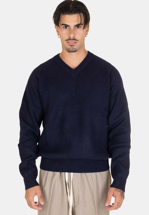 Maglione a coste blu navy con scollatura a V, realizzato in lana, dotato di maniche lunghe e orlo aderente. La texture è morbida e presenta una sottile lucentezza.