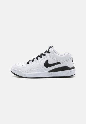 Witte sportieve schoen met zwarte accenten, voorzien van een glad leren bovenwerk, geperforeerde neus en een stevige rubberen zool.