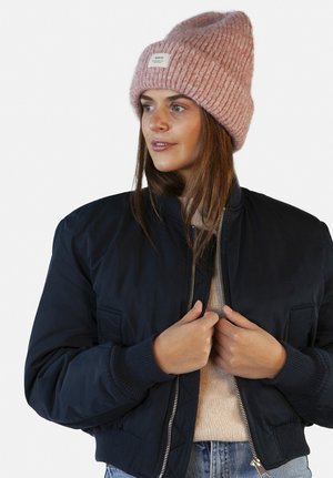 Marine bomberjack met ribgebreide manchetten, voorzien van zijzakken en een zilveren rits. Gepaard met een gestructureerde lichtroze gebreide beanie.