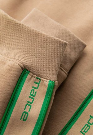 Tan sweatshirt fabric with green accent detailing on cuffs. Features textured knit and embroidered branding along the side.