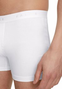 Pantaloni boxer bianchi in cotone con un morbido elastiche in vita etichettato 'FALKE'. Texture liscia con un design aderente.
