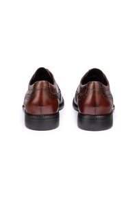 Scarpe da uomo in pelle marrone con finitura liscia, cuciture decorative e punta rotonda. Tacco nero con superficie testurizzata.