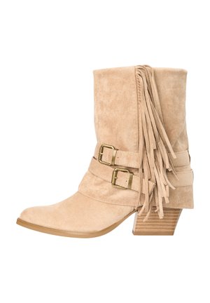 Bota de ante beige hasta media espinilla con tacón de madera apilado, dos correas con hebilla de latón y flecos decorativos de ante en el lateral.