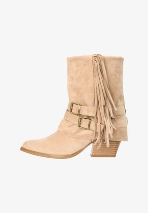 Bota de ante beige hasta media espinilla con tacón de madera apilado, dos correas con hebilla de latón y flecos decorativos de ante en el lateral.