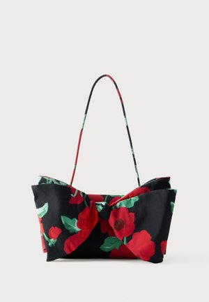 Floral shoulder bag featuring black fabric with red and green flower patterns, bow detail, and a thin, colored handle.