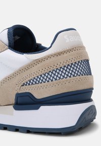 Sneaker blu e beige con tomaia in suede e mesh, suola intermedia bianca imbottita e suola in gomma testurizzata, con logo sul tallone.