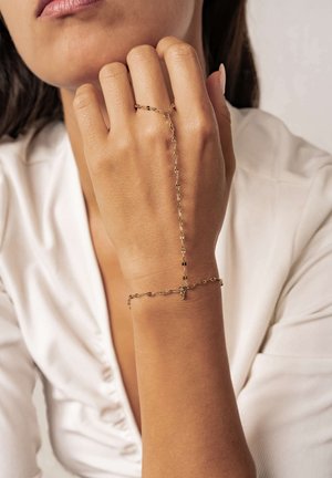 Gold chain bracelet with delicate links, featuring a decorative hand chain connecting to a ring. Smooth texture, minimalist design.