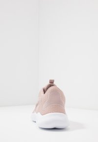 Baskets rose clair avec un dessus en tricot texturé, un col rembourré et une semelle en caoutchouc blanche. Présente une petite languette à l'arrière.