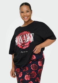 Zwart oversized t-shirt met een grote rode rozenafdruk en witte tekst. Gecombineerd met een rok met bloemenpatroon in tinten van rood en marineblauw.