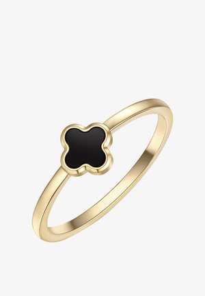 Anillo delgado de oro con una piedra negra en forma de trébol de cuatro hojas, engastada en un bisel elevado sobre un fondo blanco.