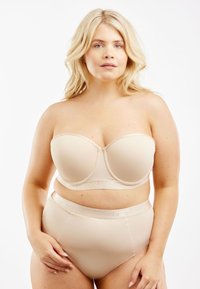 Beige strapless bh van soepel stof, met onderlijnsteun en logo-band; gecombineerd met hoge bijpassende huidskleurige slipjes in vergelijkbaar materiaal.