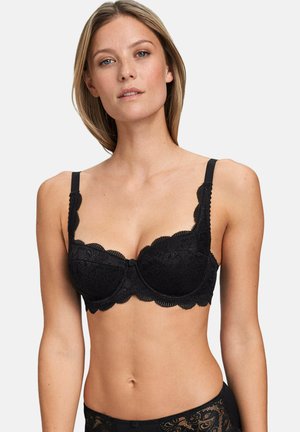 Black lace bra with scalloped edges, underwire support, and adjustable straps. Features floral pattern and central button detail.