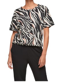 Camiseta de manga corta en crema con un patrón de rayas de cebra en negro y naranja. Corte holgado, cuello redondo, tejido suave, combina con pantalones negros.