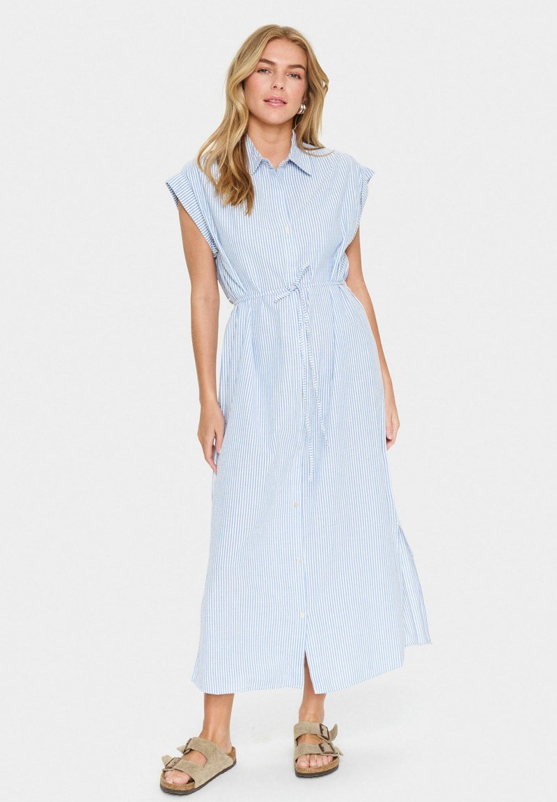 Vestito maxi a righe blu e bianche con bottoni, dotato di maniche corte, cintura da annodare in vita e una fessura laterale. Il tessuto sembra leggero.