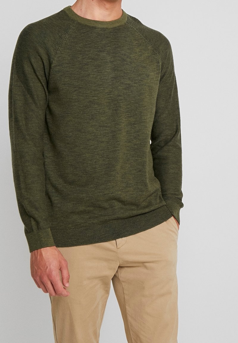 Olivgrüner gestrickter Pullover mit Rundhalsausschnitt, gerippten Bündchen und Saum. Verfügt über eine strukturierte Oberfläche, figurnahe Passform und Raglanärmel.