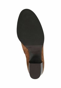 Suela de zapato de ante marrón con una superficie de goma negra texturizada. Presenta un tacón bajo y el nombre de la marca en relieve "Caprice". Talla marcada como "4½".
