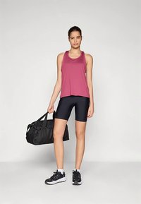 Débardeur léger bordeaux à coupe décontractée, associé à un short de cyclisme noir. Sac de sport noir et chaussures de sport foncées complètent le look.
