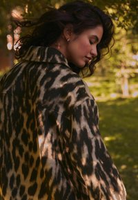 Leopardi kuvioinen takki lämpimissä ruskean ja beigen sävyissä, jossa on kaulus ja rento istuvuus. Pehmeä kangas, jossa on teksturoitu pinta.