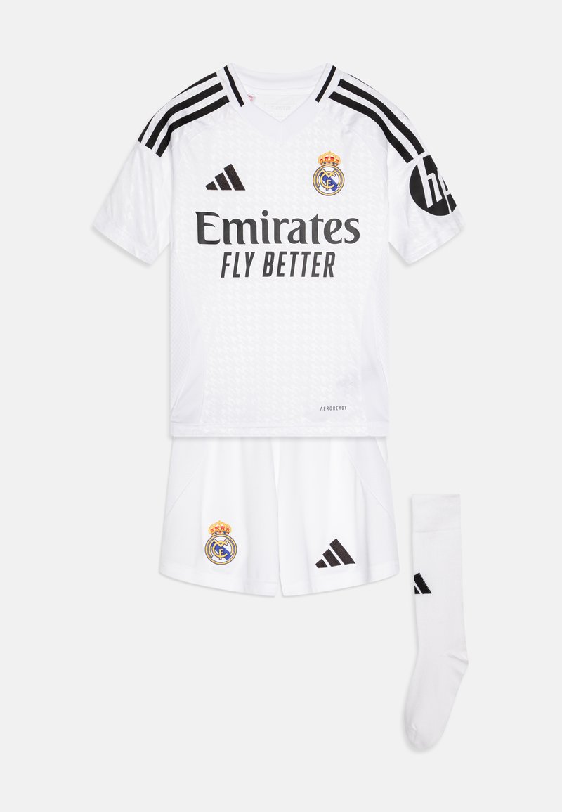 Equipación de fútbol blanca que incluye una camiseta con franjas negras, el logo "Emirates Fly Better", pantalones cortos con el escudo del club y medias blancas sólidas.