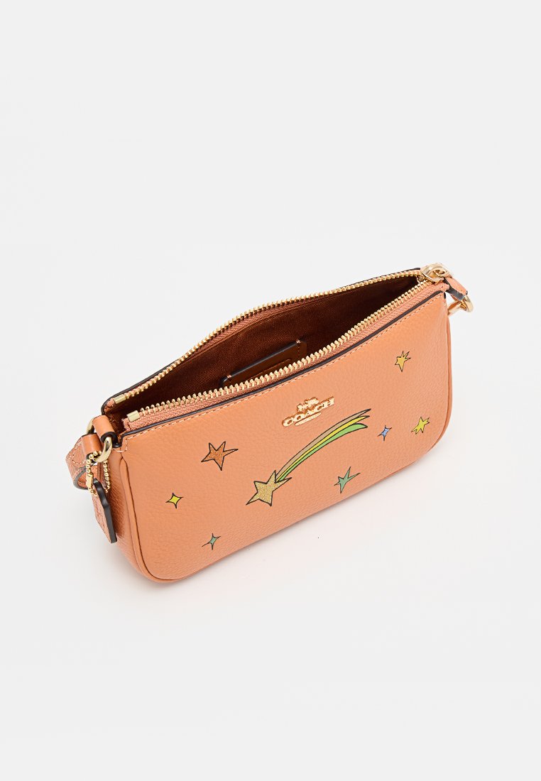 Kleine beige Coach polstasje met gouden ritssluiting, meerkleurige vallende sterren ontwerpen en een afneembare leren band op een witte achtergrond.