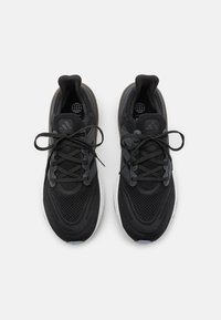 Baskets de sport noires avec un dessus en mesh, accents texturés, design épuré, bout rond et semelle en caoutchouc. Les lacets sont dans un motif croisé standard.