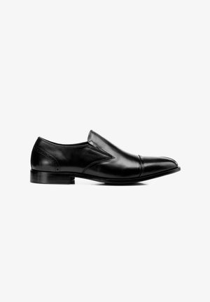 Zapato formal negro de cuero sin cordones con tacón bajo y costuras decorativas sobre fondo blanco, visto de lado.