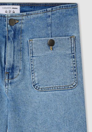 Jeans in denim azzurro chiaro con una tasca posteriore fissata da un bottone metallico nero, con dettagli di cucitura visibili e un'etichetta in tessuto in vita.