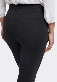 Mörkgrå högmidjade leggings med en slät yta, utrustade med två bakfickor och en åtsittande design. Diskret sömnadsdetalj längs sömmarna.