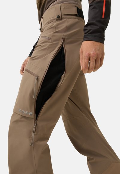 Beige technische Hose mit Reißverschlussbelüftungen und mehreren Taschen, mit schlanker, glatter Textur und verstellbarem Bund.