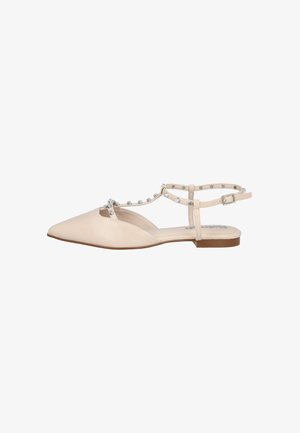 Sandalia plana beige con punta en pico, tira en el tobillo y tachuelas plateadas a lo largo de la tira en T y cierre de hebilla.