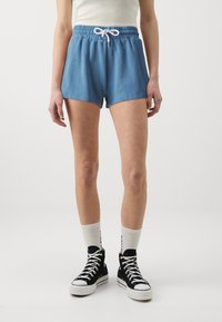 Blue cotton shorts with an elastic waistband and white drawstring, paired with black high-top sneakers and white ankle socks.