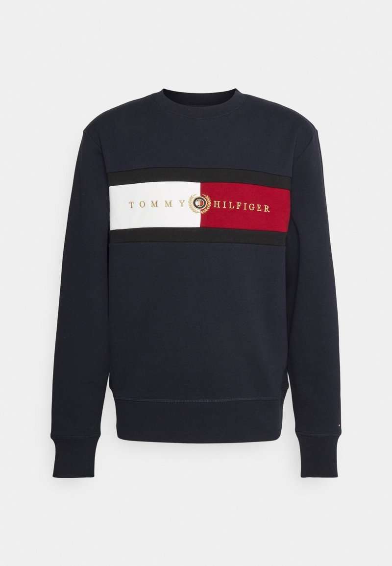 Sudadera navy con cuello redondeado, que presenta un diseño de franjas horizontales en rojo, blanco y negro con el texto en dorado "Tommy Hilfiger".