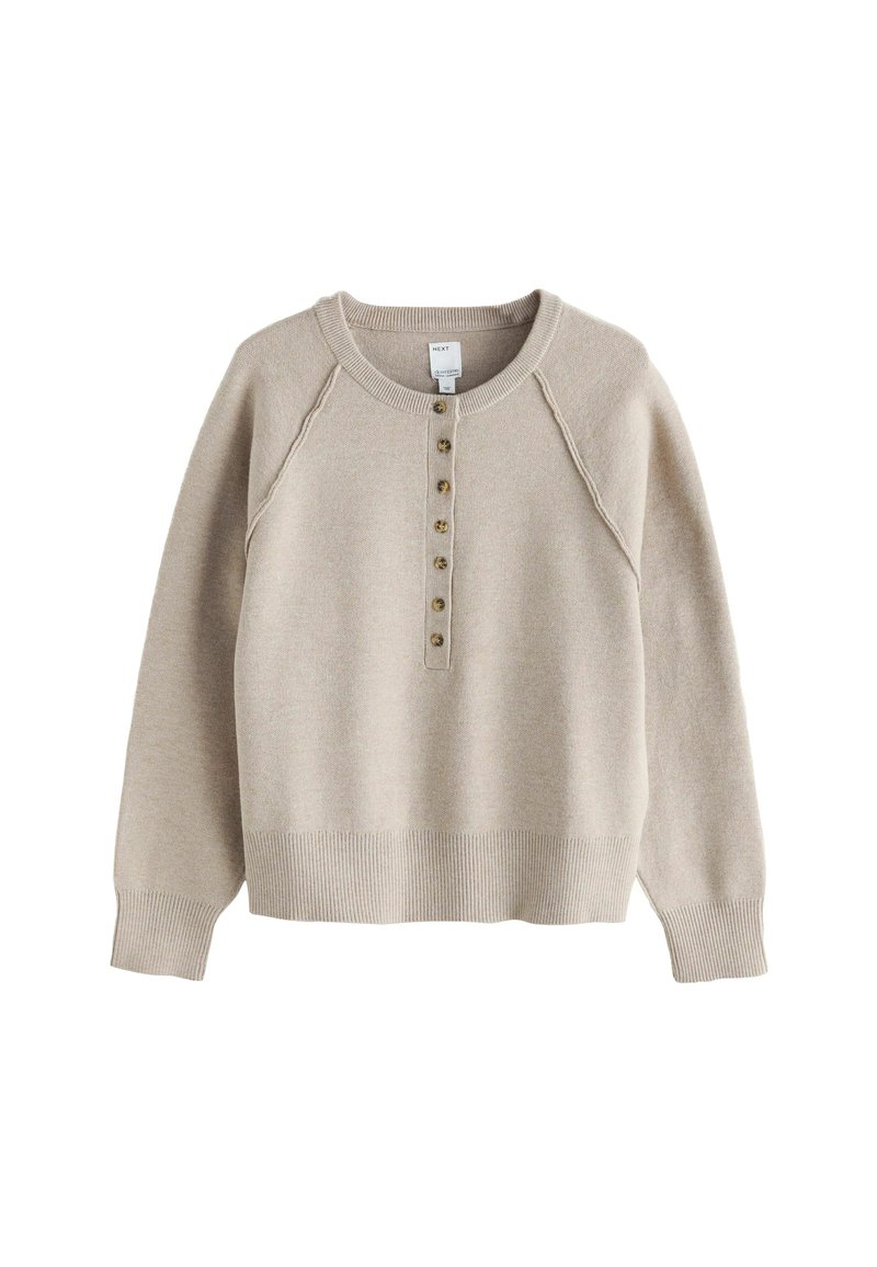Valkoinen vaalean beige neule, jossa on pyöreä pääntie, raglan-hihat ja viiden napin lista. Varustettu ribatulla hihansuulla ja helmalla, valmistettu pehmeästä materiaalista.