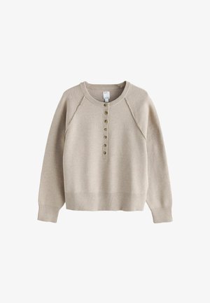 Beige sweater with a crew neckline, button placket, and ribbed cuffs and hem. Soft texture and relaxed fit, featuring raglan sleeves.