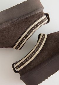 Pruunist seemisest materjalist platvormkingad, millel on tekstureeritud viimistlus, küljel kreemjas ja pruunides triipudes pael ning logo aktsendid.