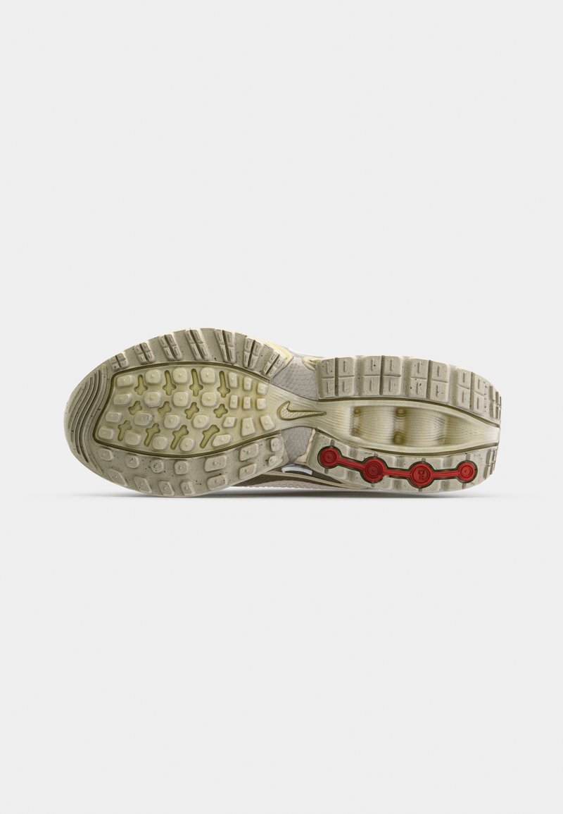Nike-Schuhsohle mit strapazierfähiger Gummisohle, die eine Mischung aus hellen und dunklen Beigetönen aufweist. Rote, runde Akzente im Fersenbereich.