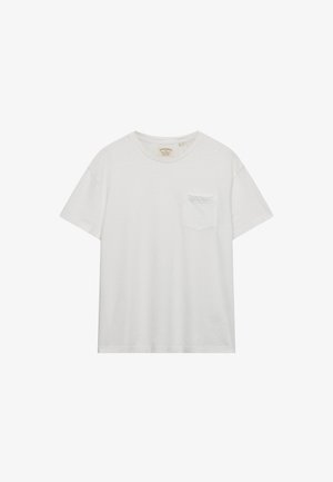 T-shirt blanc à manches courtes et col rond, avec une petite poche sur la poitrine et une étiquette de marque visible à l’intérieur du col.