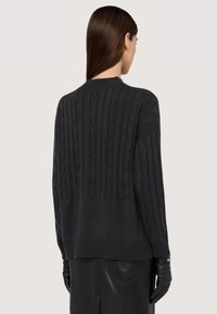 Ciemnoszara dziergana sweter z wzorem w warkocze, z prążkowanym dekoltem i luźnym krojem. Tył ozdobiony pionowymi teksturowanymi paskami.