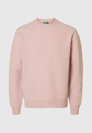 Rožinis megztinis su apvalia iškirpte, kūgine rankogaliu ir apačia, minkšta tekstūra ir laisvu kirpimu. Minimalistinis dizainas be papildomų raštų.