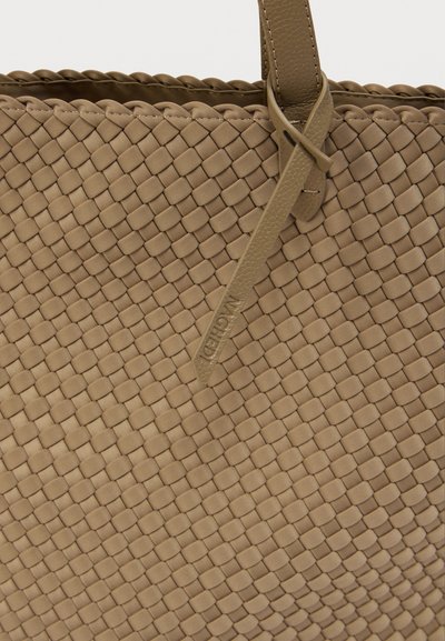Μπεζ υφαντή δερμάτινη τσάντα tote με υφή και σχέδιο crosshatch, με ανθεκτικές λαβές και διακριτική εμβληματική ετικέτα με ανάγλυφο λογότυπο.