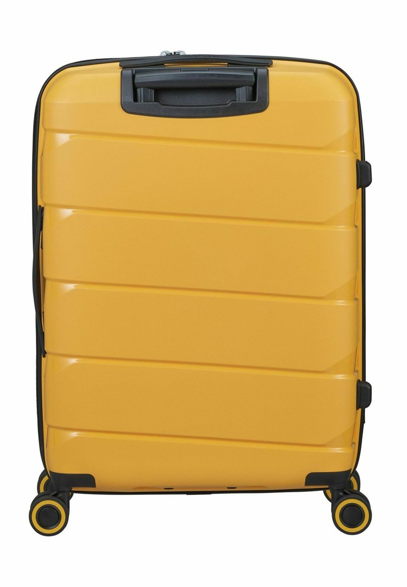 Geel harde koffer met slanke ribbels, zwarte accenten, een handvat aan de bovenkant en vier dubbele wielen voor mobiliteit. Textuur op het oppervlak verbetert de grip.