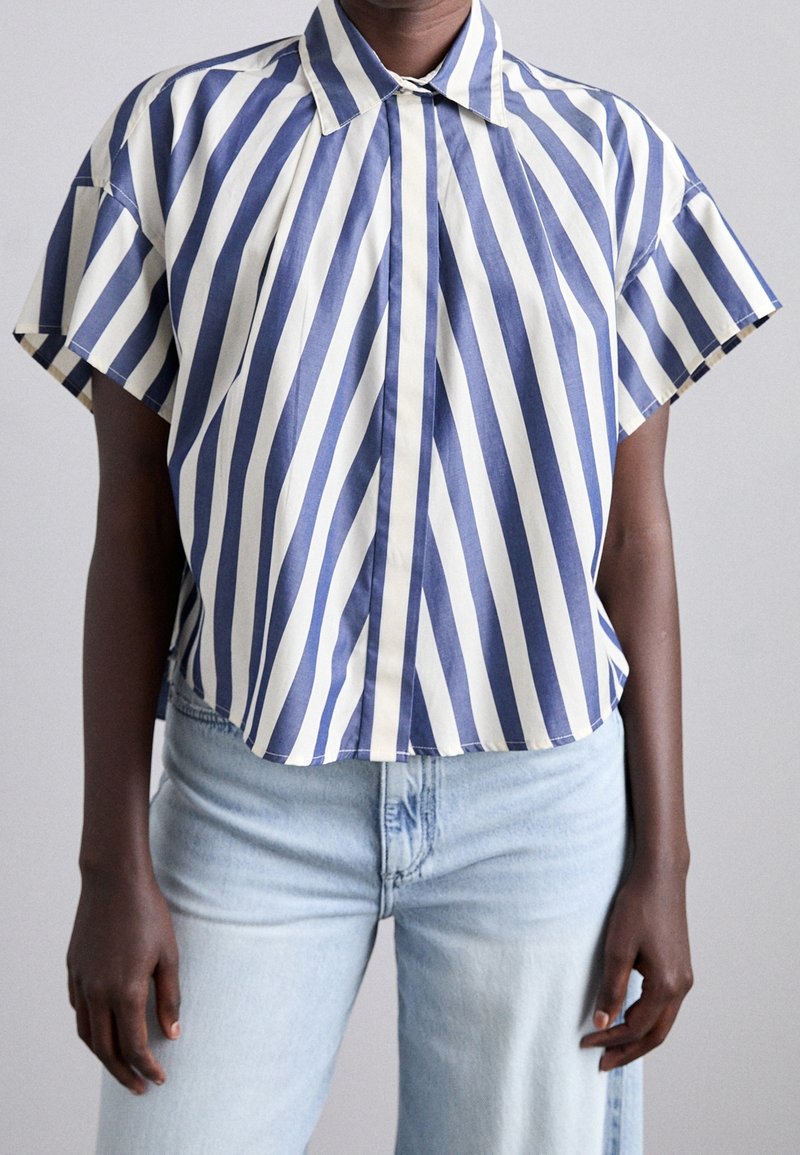 Blue and cream horizontal striped short-sleeve shirt with a pointed collar and loose-fitting design; made of lightweight fabric.