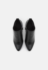 Botines de cuero negro con punta afilada, textura suave y cierre interior con cremallera. Cuenta con un tacón bajo y estructurado.