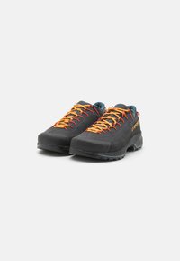 Schwarze Wanderschuhe aus Wildleder mit orangenen Schnürsenkeln. Sie verfügen über eine Gummisohle, einen gepolsterten Schaft und ein Logo an der Seite. Leichtes Design.