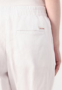 Svijetle, elastične hlače s pojasom s stražnjim džepom na kojem se nalazi mala oznaka s Calvin Klein logoom. Mekana, teksturirana tkanina s opuštenim krojem.