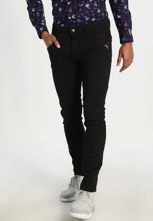 Zwarte skinny jeans met een gladde textuur, vijf zakken en een klein driehoekig logo detail op de rechter voorzak.