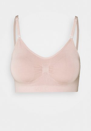Unlined bralette in soft, light pink fabric. Features adjustable straps, a gathered center panel, and a seamless design for comfort.
