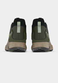 Dunkelgrüne und schwarze Wanderschuhe mit robuster Sohle, niedrigem Knöcheldesign, verstärkter Ferse und hellgrünen Akzenten.