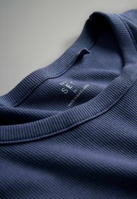 T-shirt a girocollo in maglia costina blu navy con cuciture visibili e un'etichetta con scritto "THE SET" sul colletto interno. Texture morbida.