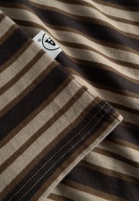 T-shirt i bomuld med vandrette striber i lysebeige, mørkebrun og taupe. Synlige sømme og et mærke nær halsudskæringen.